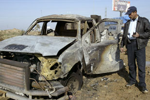 Iraqi policeman looks at blown-up car