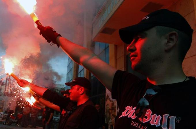 Members of the Greek extreme right Golden Dawn party hold red flares outside the town hall of Perama town