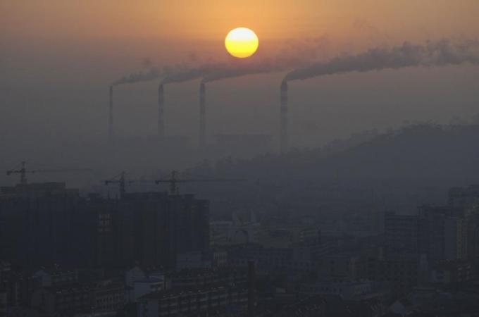 Smoke billows from the chimneys of a power plant during sunrise in Jiaxing