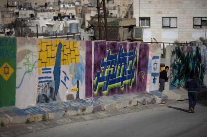 A Palestinian boy looks through the sepa