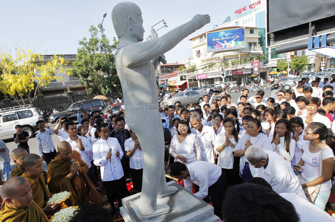 Cambodian workers pray next to a statue of former President of the Free Trade Union of the Workers