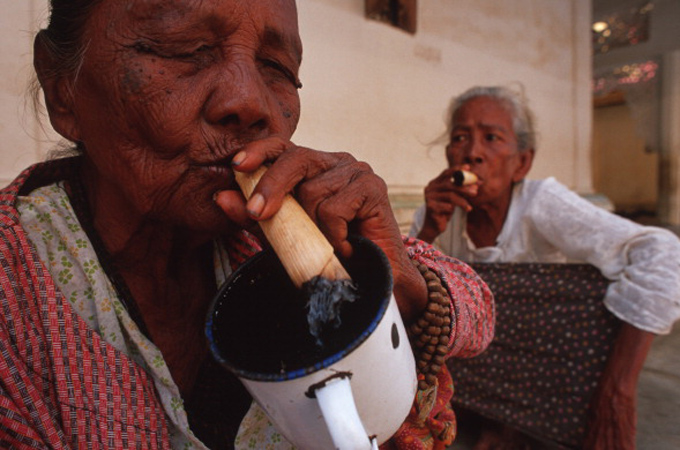 Two elderly women smoke hand-rolled cheroots at Myanmar's Shwedagon Pagoda [Getty Images]