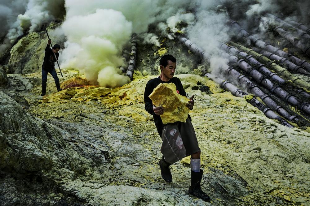 <p>A miner carries a large chunk of high-purity sulphur.</p>