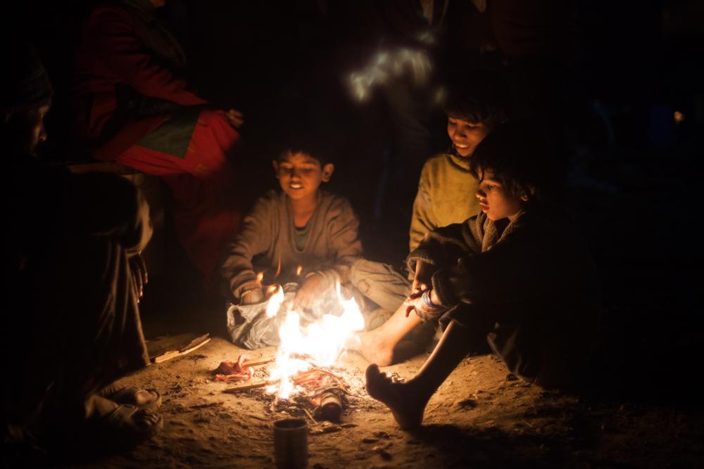 Bare foot children group around a fire to keep warm. About 900 people, including about 500 children, have been left without shelter after their shanties were demolished by authorities in north east Delhi.