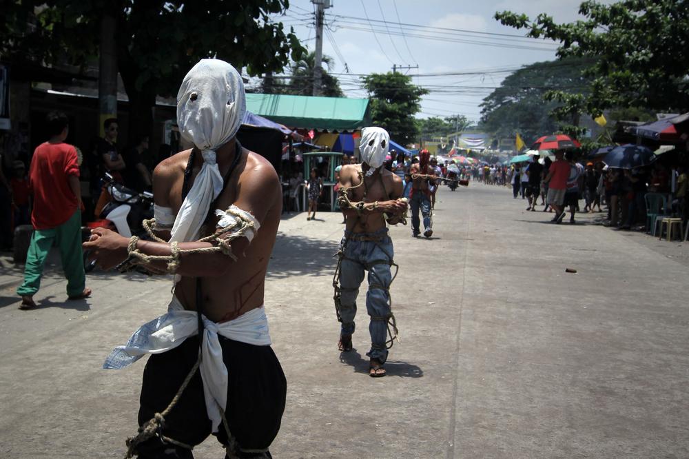<p>Hooded penitents, barefoot and tied with homemade whips, flagellate themselves as part of an annual Easter tradition in the village of Lourdes.</p>