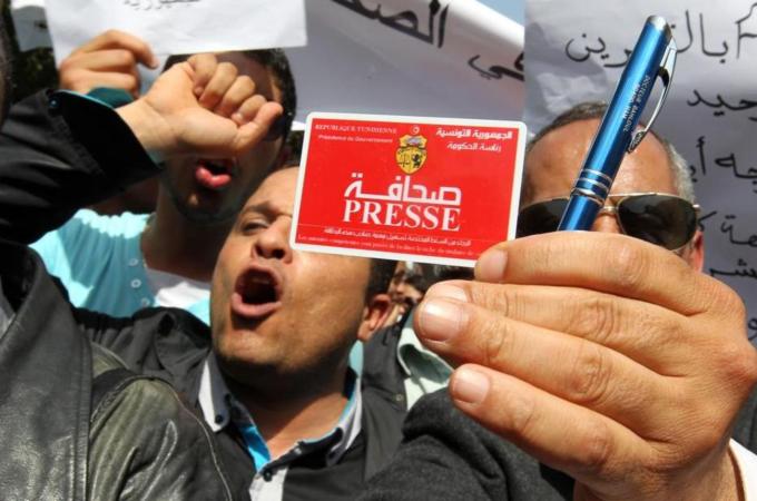 A Tunisian journalist displays his press card during a rally to mark World Press Freedom Day in Tunis [EPA]