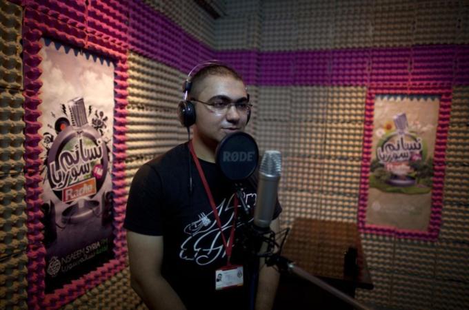 Wael Adel, 30, the manager of Nsaeem Syria radio station, records material in the studio in the northern Syrian city of Aleppo [AFP]