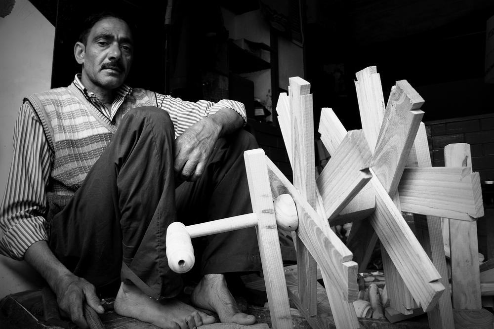 <p>Ishtiyaq Ahmad, 39, a carpenter displays a finished spinning wheel at his shop in Ael Kadal, Srinagar.</p>