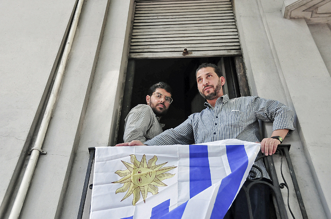 Two former prisoners at Guantanamo Bay stand on a balcony decorated with Uruguay's flag in Montevideo [AP]