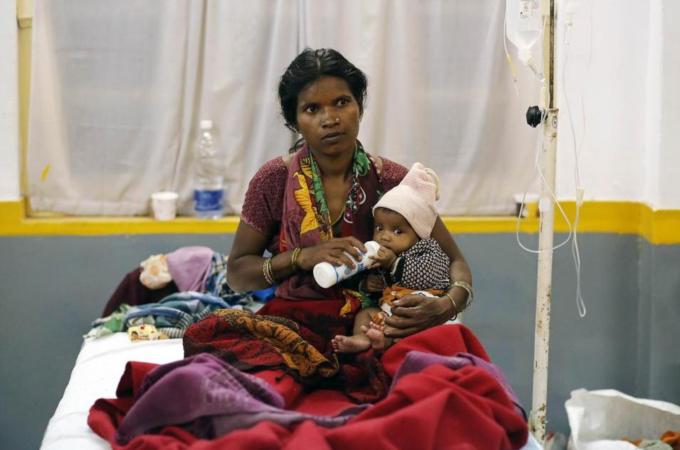 A woman, who underwent a sterilisation surgery at a government mass sterilisation camp, feeds her child while sitting on a hospital bed for treatment in Bilaspur, in the eastern Indian state of Chhattisgarh [Reuters]