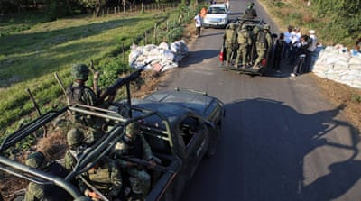 Mexican soldiers inspect a checkpoint by members of a self-defence group [EPA]