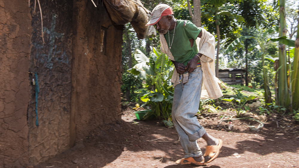 Minani stumbles back to his hut after another all night drinking session. He has no money, but somehow manages to buy waragi [AJ Heath/Al Jazeera]