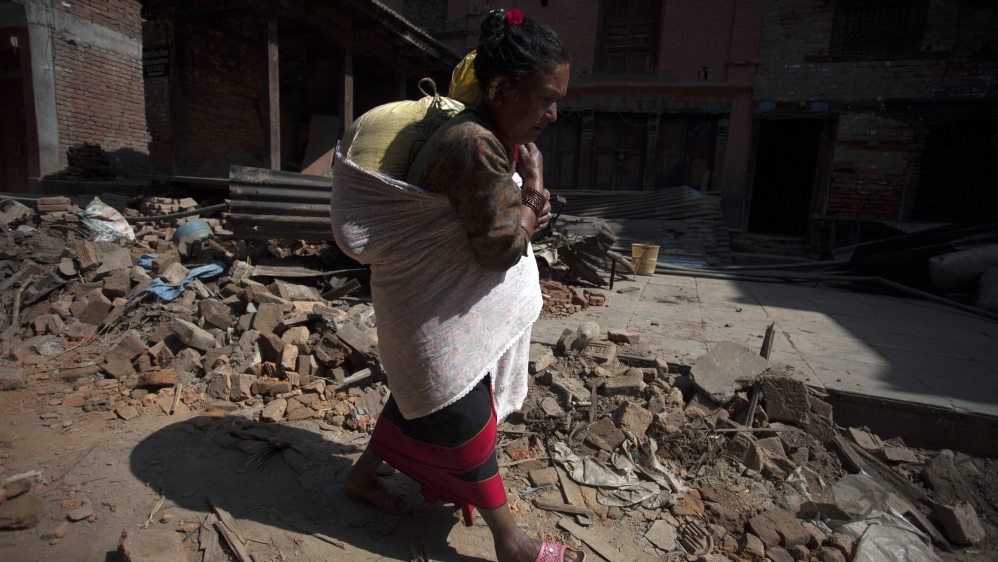 A Nepalese earthquake survivor carries her belongings a day after a major earthquake [EPA]