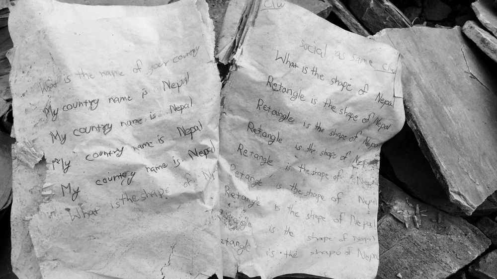 Digging for memories, Paudel finds his son's school backpack and his notebook [Tiffany Ang / Al Jazeera]