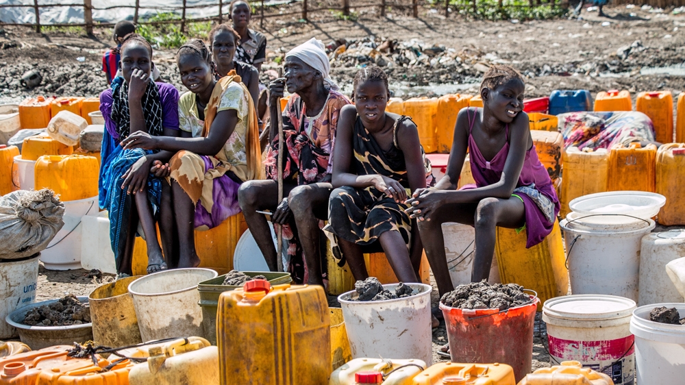 Women line up for hours to collect water using hand pumps in the camp [Ashley Hamer/Al Jazeera]