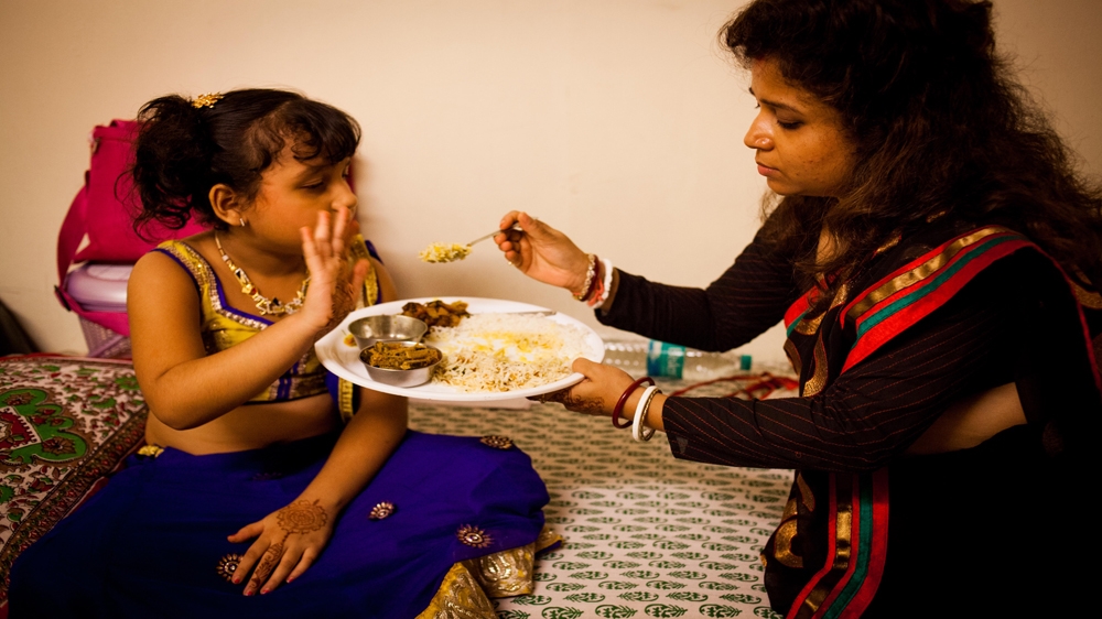 Eight-year-old Palak Dey is fed her dinner by her mother, Mamta Dey, at 11pm in the dressing room on set. Palak often spends 12 hours a day on set and sometimes has to skip school to accommodate her shooting schedules [Karen Dias]