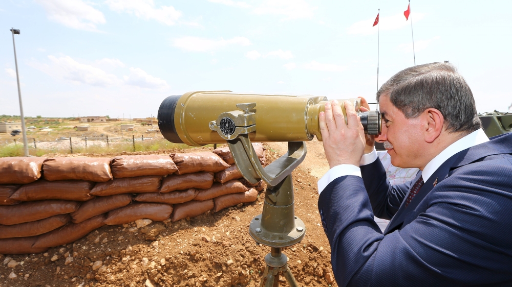 Turkish Prime Minister Ahmet Davutoglu looks through binoculars at Syria from a Turkish military base at the border with Syria [Reuters]