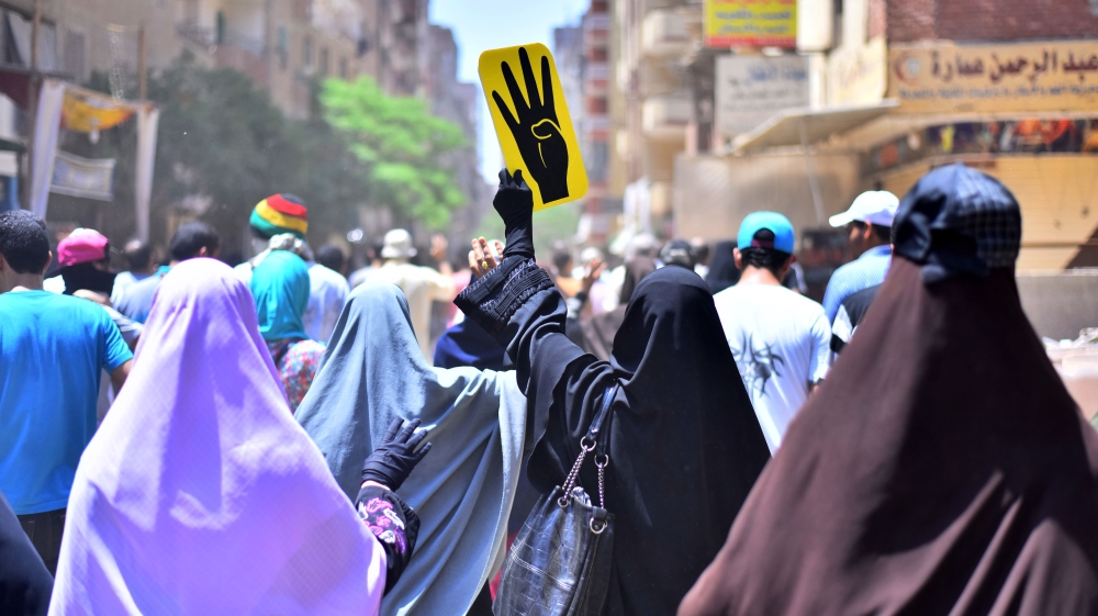 Female supporters of the Muslim Brotherhood gesture and hold up a sign picturing a hand with four fingers, a symbolic gesture of the deadly crackdown on MB supporters at two sit