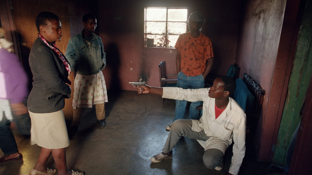 In this photograph taken in 1992, an Inkatha Freedom Party supporter brandishes a handgun and fools around in Dobsonville hostel, Soweto, during a police raid to search for illegal weapons [Greg Marinovich]