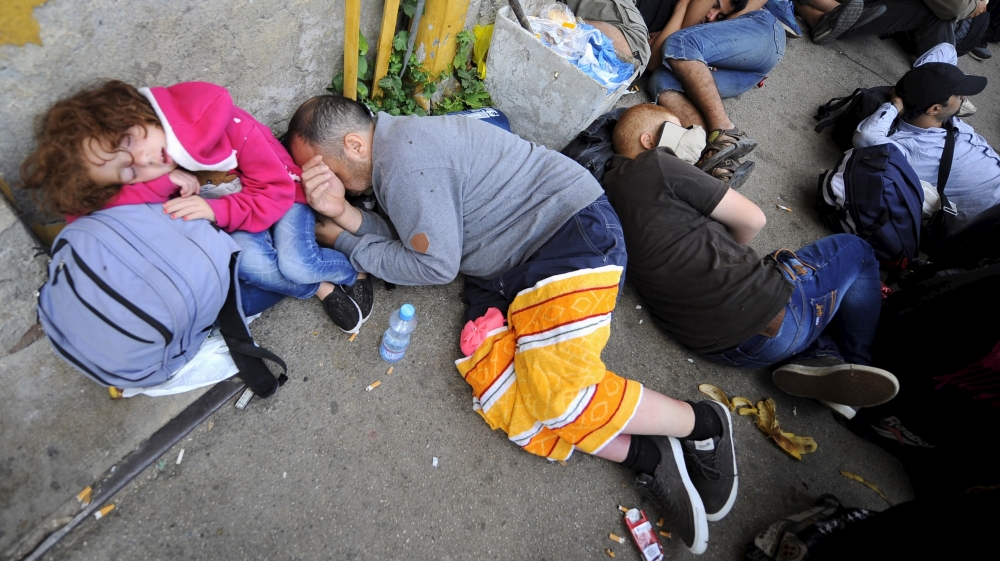 A group of refugees who have made through police blockades rest at the Gevgelija railway station