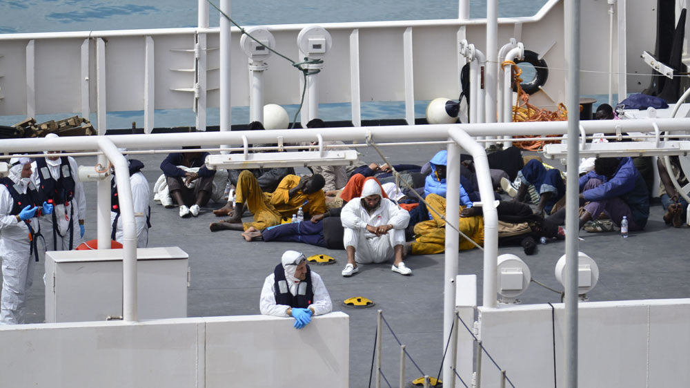 Survivors of a smuggler's boat that overturned off the coast of Libya huddle on the deck of an Italian Coastguard ship [AP]