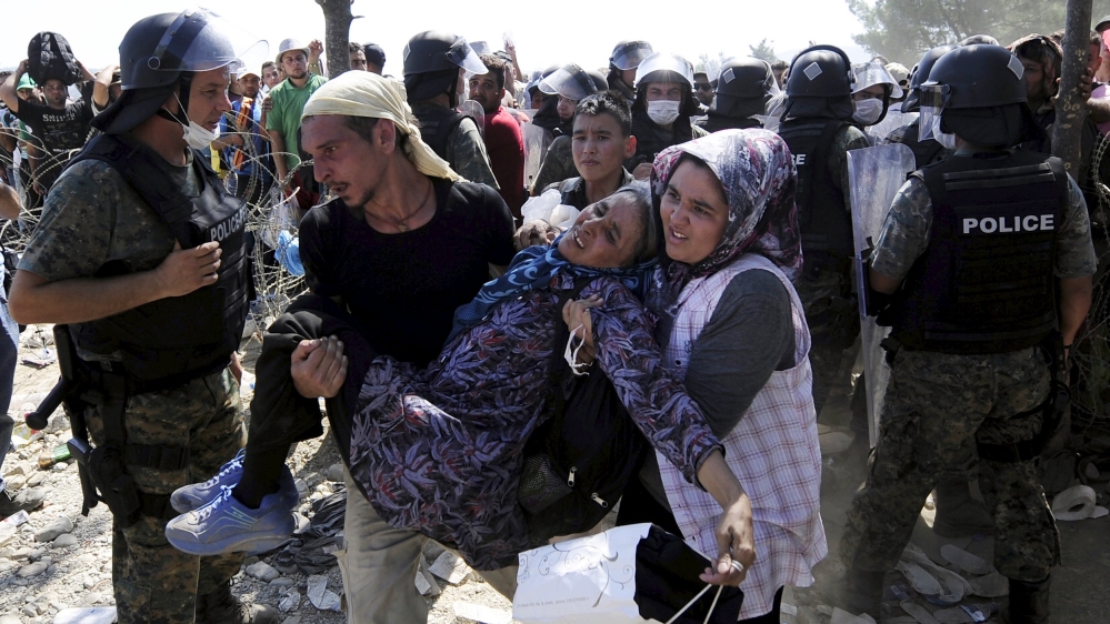 Migrants rush to cross into Macedonia after Macedonian police allowed a small group of people to pass through a passageway [REUTERS]