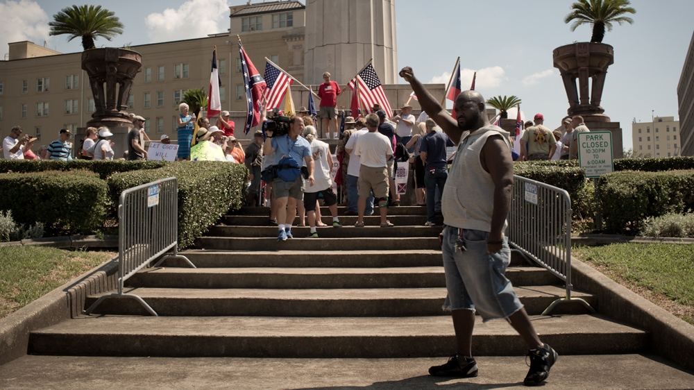 Russell Robinson raises his right fist, a symbol of Black Power, near a protest to protect monuments of Confederate leaders [Roopa Gogineni]