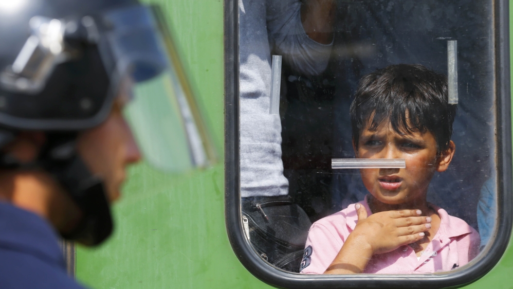 A migrant boy looks at a Hungarian policeman at the railway station in the town of Bicske