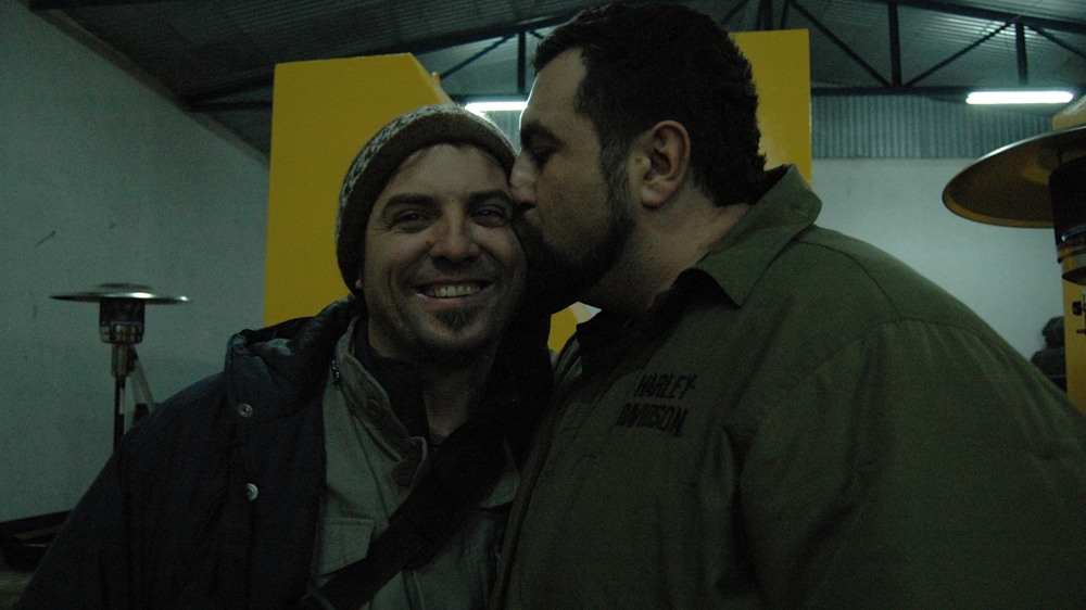 The author, left, and his friend Fisnik on the eve of Kosovo's independence, in front of one part of the Newborn statue that Fisnik had designed for the new state