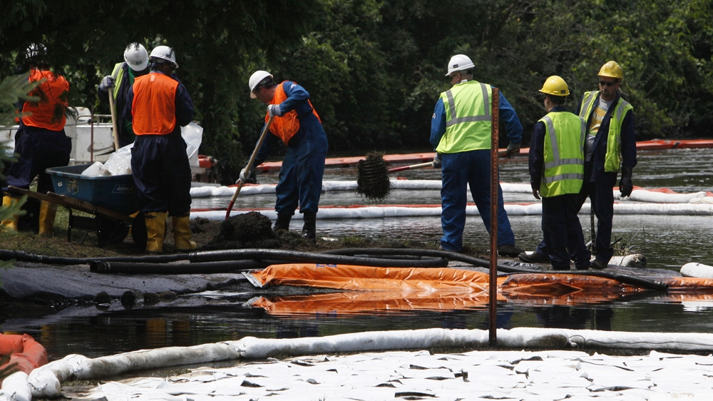 Crews use booms and absorbent materials to clean up oil from a ruptured Enbridge pipeline near the Kalamazoo River [Paul Sancya/AP]