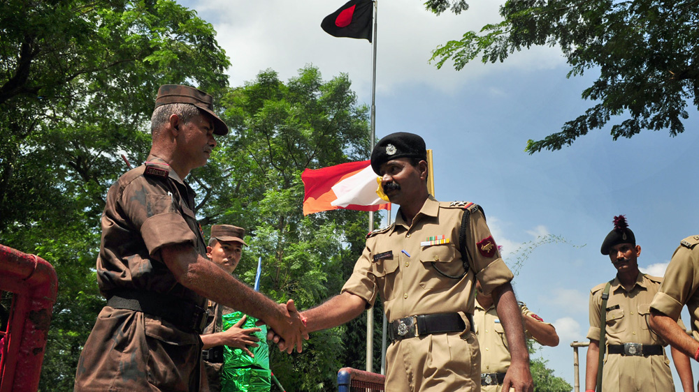 Indian and Bangladesh border guards greet each other - but relations have sometimes frayed over the fence [Pinaki Das/Al Jazeera]