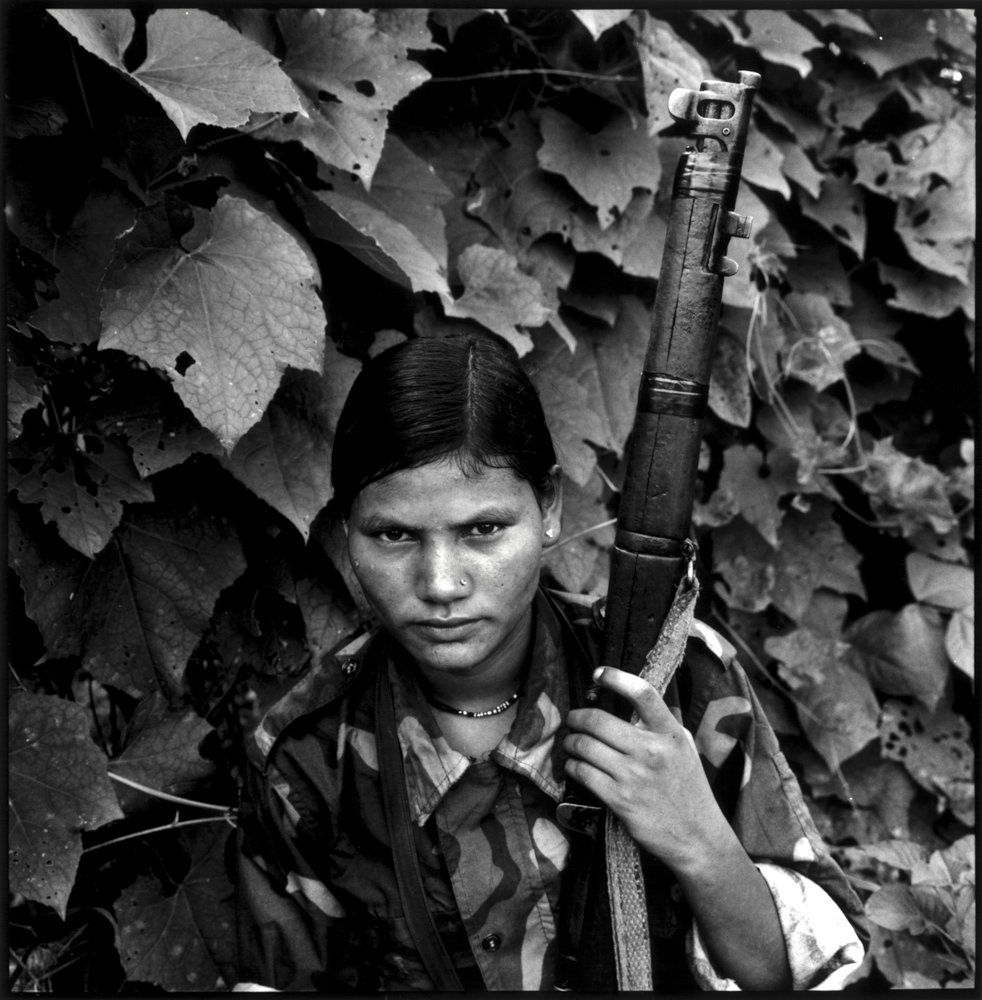 Philip Blenkinsop first came to Nepal in 2001 to photograph the Maoist guerrillas. From 'In the Shadow of Hope' [Philip Blenkinsop]Film extras with exotic hairdos take a break during filming of Bernardo Bertolucci's Little Buddha in Bhaktapur. The shooting of the film was one of the major events in the valley in those more sedate times [Bikas Rauniar]Nepal Workers and Peasants Party, 'NeMaKiPa', boss Narayan Man Bijukchhe AKA Rohit (third from right) and senior diplomats from the North Korean embassy attend a sports programme organised to mark the birth anniversary of Kim Jong-il in Bhaktapur. The valorisation of North Korea was a feature of national politics until very recently [Bikas Rauniar]From 'In the Shadow of Hope' [Philip Blenkinsop]An Armed Police Force officer is lifted up by colleagues 120 hours after he rescued a 15-year-old from the rubble of a collapsed building [@saagarchhetri/Nepal Photo Project]Ritual Dancers, Limitang Village, Humla, 1985. In Limitang the ritual movement of masked and costumed village men reenacts the passage of the spirits of deceased beings into the next life. From 'Portraits of Nepal' [Kevin Bubriski] 