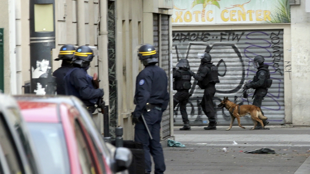 Members of special French RAID forces with a police dog and French riot police secure the area during an operation in Saint-Denis, near Paris