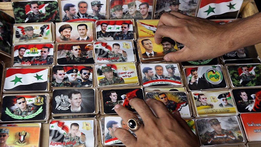A Syrian vendor arranging pins displaying portraits of Assad with Hezbollah leader Hassan Nasrallah [Getty]