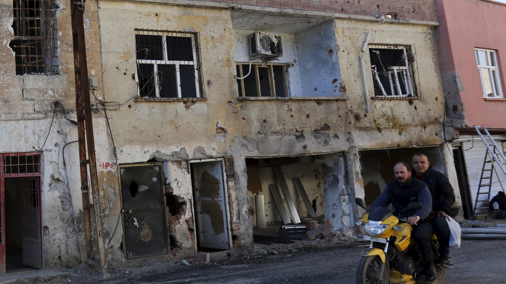 Men drive past a building which was damaged during the security operations and clashes between Turkish security forces and Kurdish militants, in the southeastern town of Silvan in Diyarbakir province,