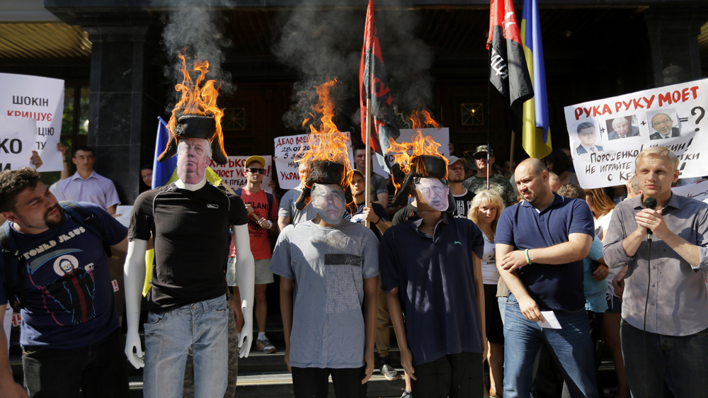 Anti-corruption activists burn caps on mannequins that represent the Prosecutor General of Ukraine