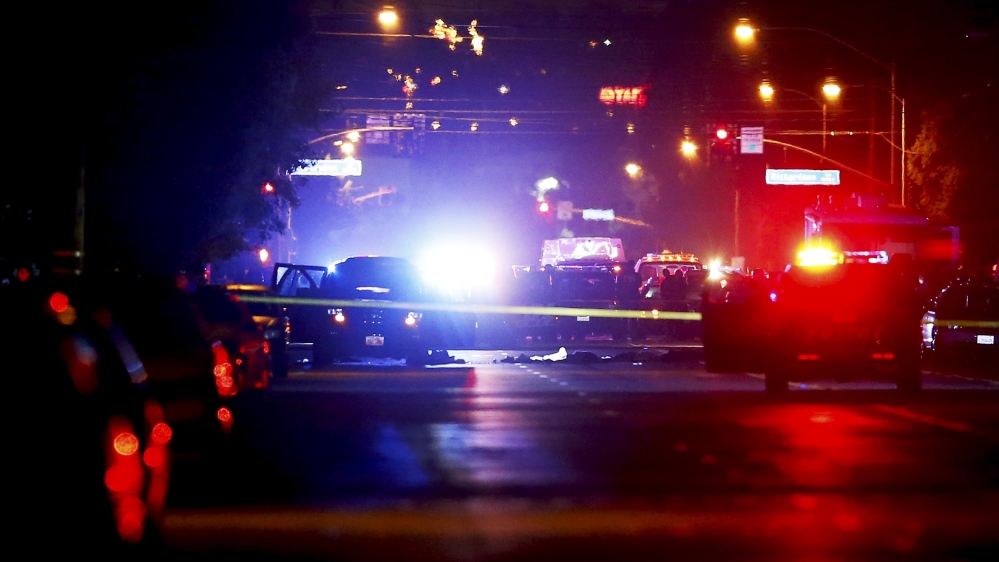 Police vehicles line the street around a vehicle in which two suspects were shot following a mass shooting in San Bernardino