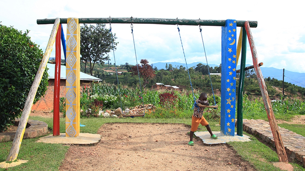  A child plays on a set of swings in the gardens surrounding L'Esperance orphanage [Anais Lopez/Al Jazeera]