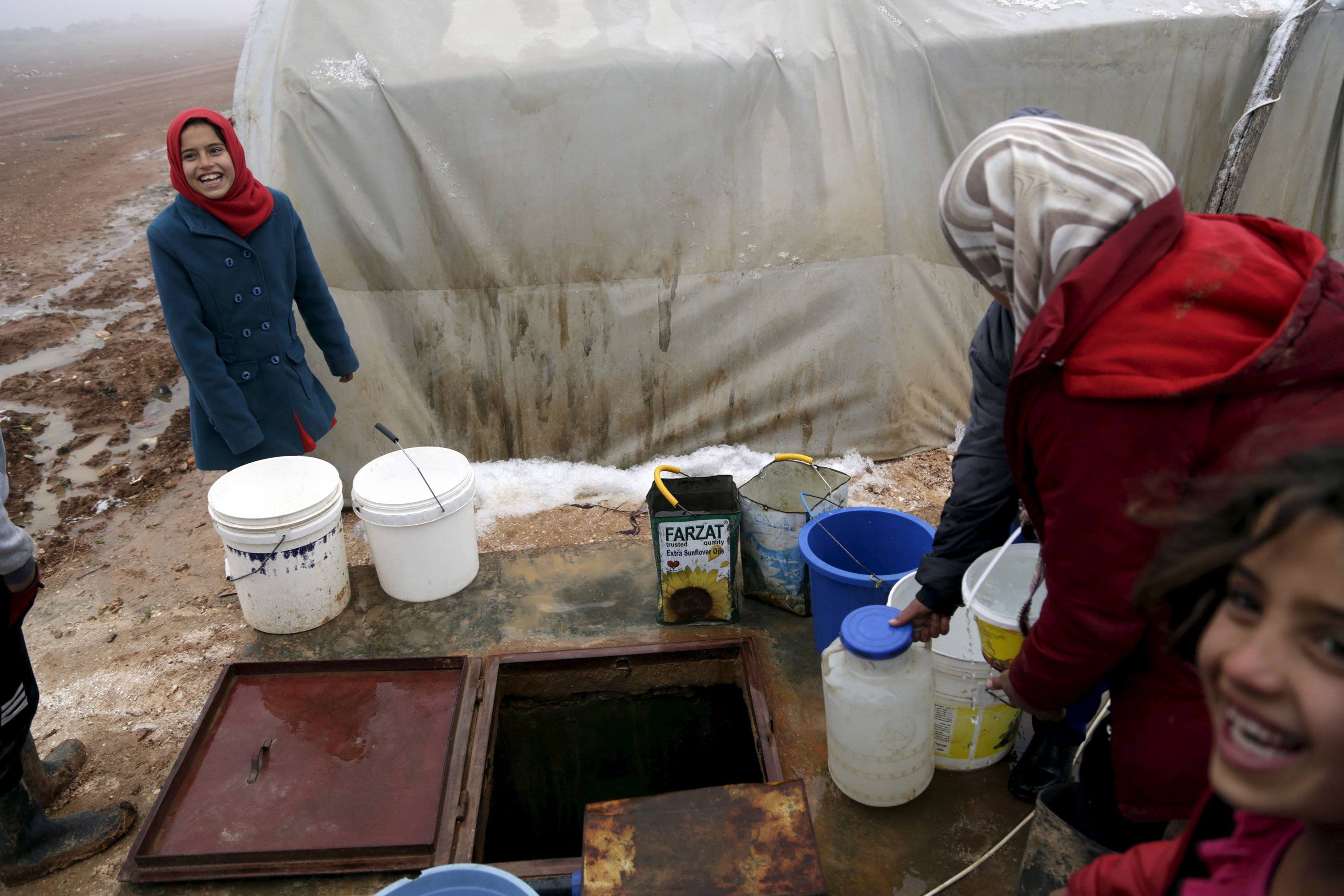 Internally displaced Syrians fill buckets with water sourced from an underground well [Reuters]
