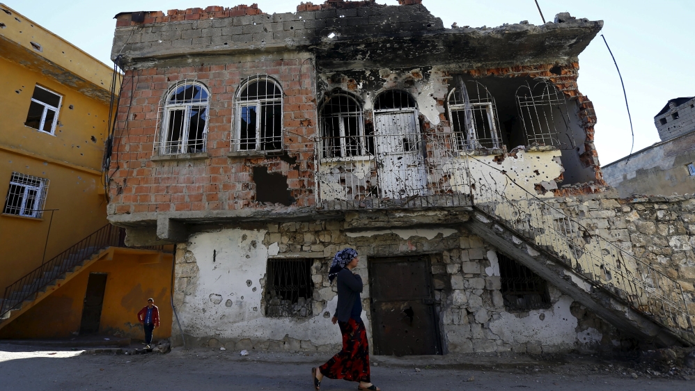 A woman walks past a building which was damaged during the security operations and clashes