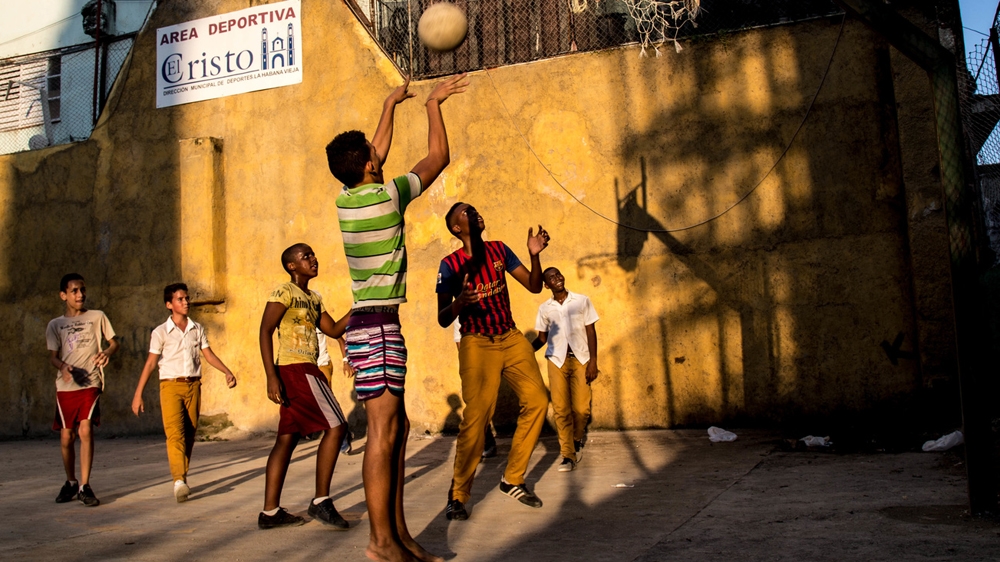 A barefoot boy pulls up to shoot a jumper on a dusty basketball court in Old Havana [Tomas Ayuso/Al Jazeera]