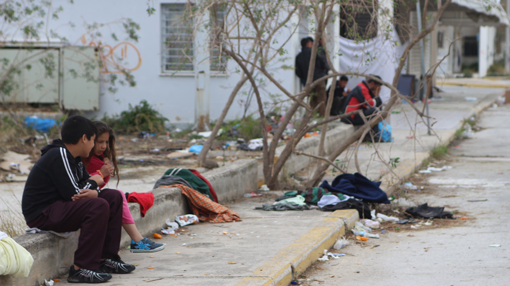Two Afghan children talk on the grounds of the defunct old Athens airport where they are being given temporary shelter [John Psaropoulos/Al Jazeera]