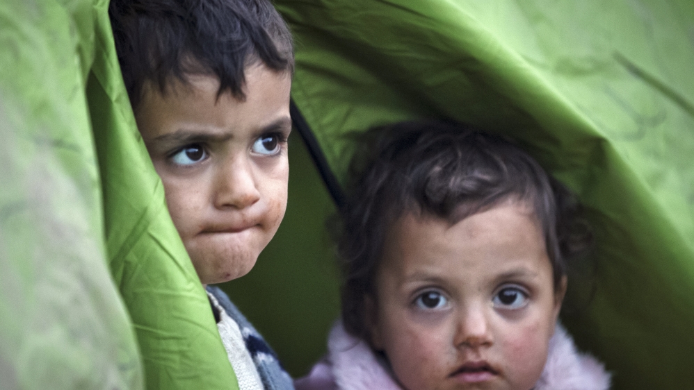 Children peer from a tent at a northern Greek border station [AP]
