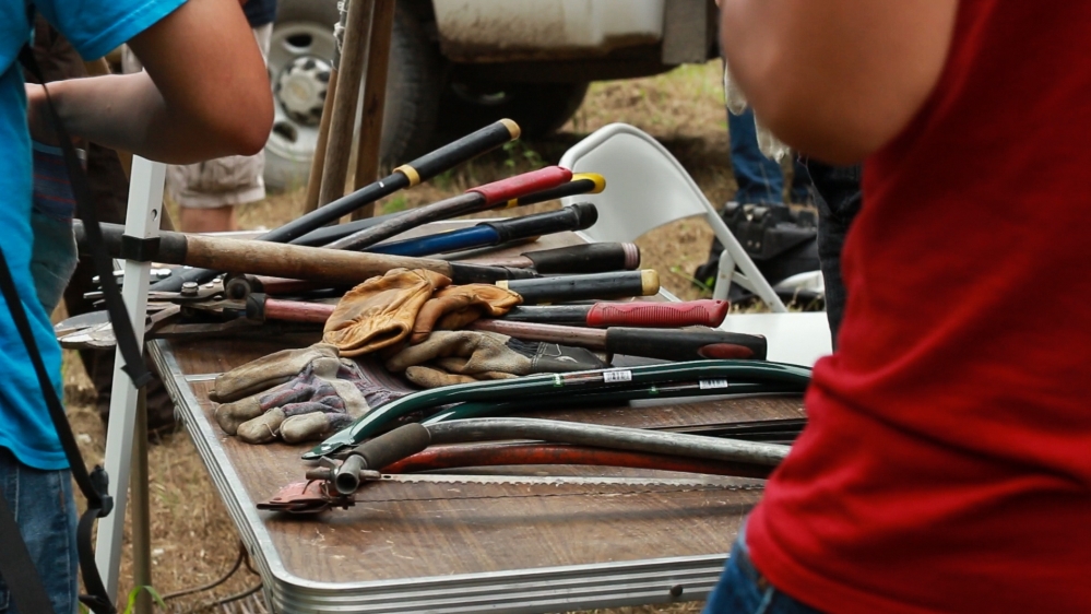 Volunteers gather their wild gardening tools to cut back and clear out other plant species that are currently out-competing with the fragile river cane for resources [Nicholas Linn/Al Jazeera]