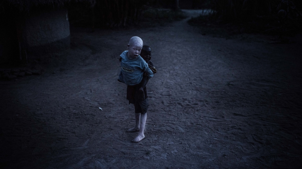 Semuju carries his youngest sister Marry, and tries to stop her from crying [Fredrik Lerneryd/Al Jazeera]