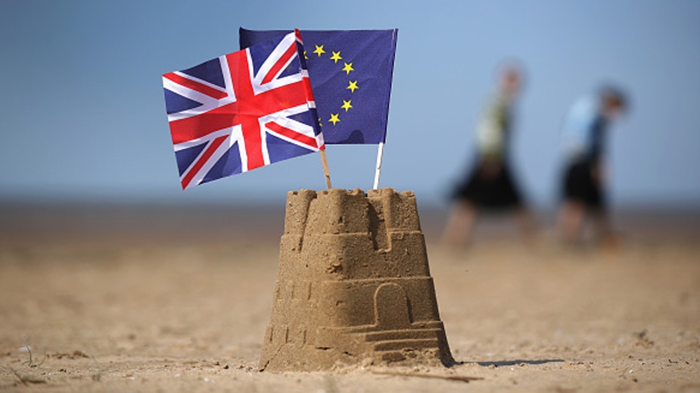 The flag of the European Union and the Union flag sit on top of a sand castle on a beach in Southport, United Kingdom [Getty]