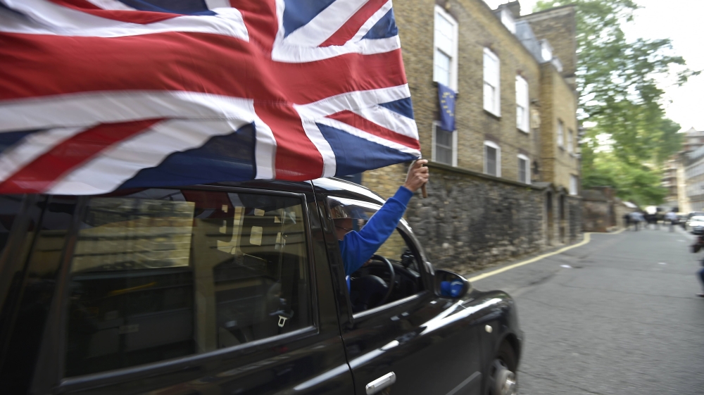 A taxi driver holds a Union flag, as he celebrates following the result of the EU referendum, in central London
