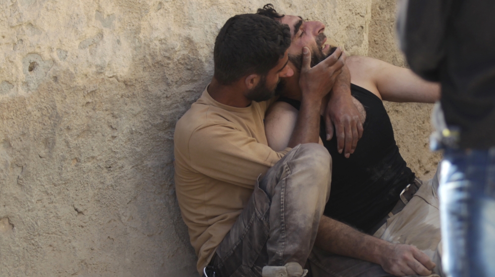 A civil defence member comforts his comrade at a site hit by airstrike in the rebel-controlled area of Maaret al-Numan town in Idlib province