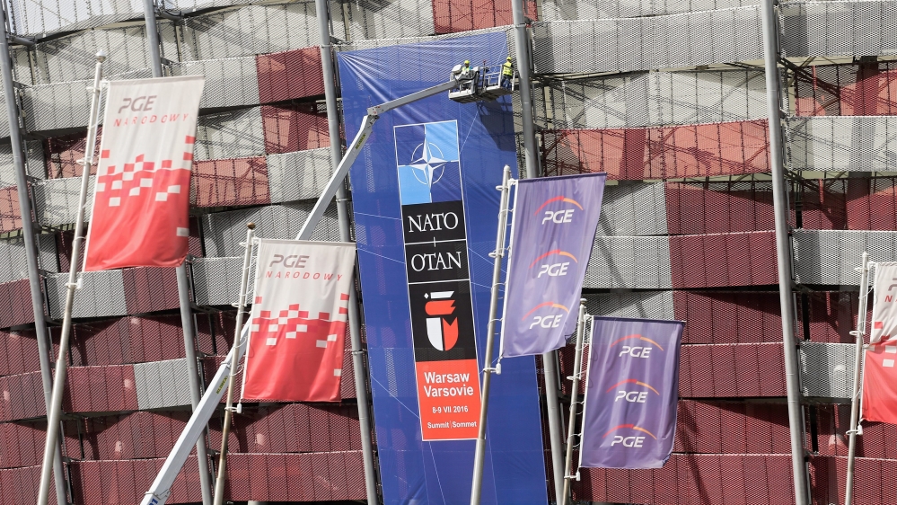 Workers place banners in preparation for the NATO Warsaw Summit in Warsaw, Poland [EPA]