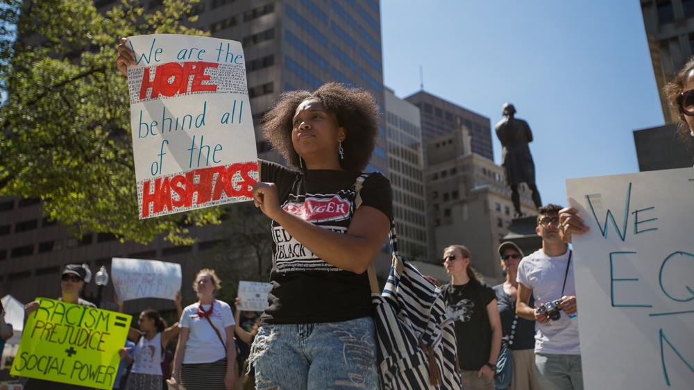 Shalece Perryman-Welch holds up a sign that reads, 'We are the hope behind all of the hashtags,' outside Faneuil Hall  [Carolyn Bick/Al Jazeera]  